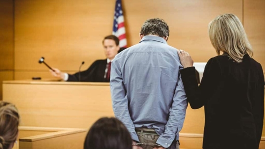 guy in blue shirt standing next to woman in black jacket in a courtroom