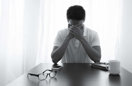man sitting at table with hands on face